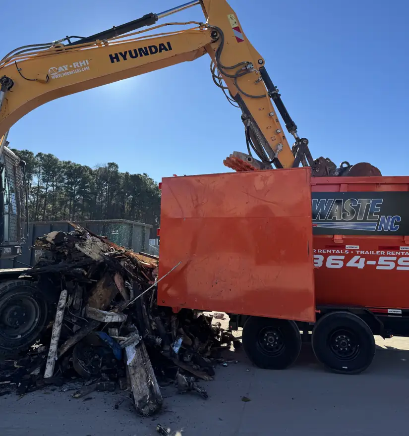 Excavator loading demolition debris into an EZ Waste dumpster